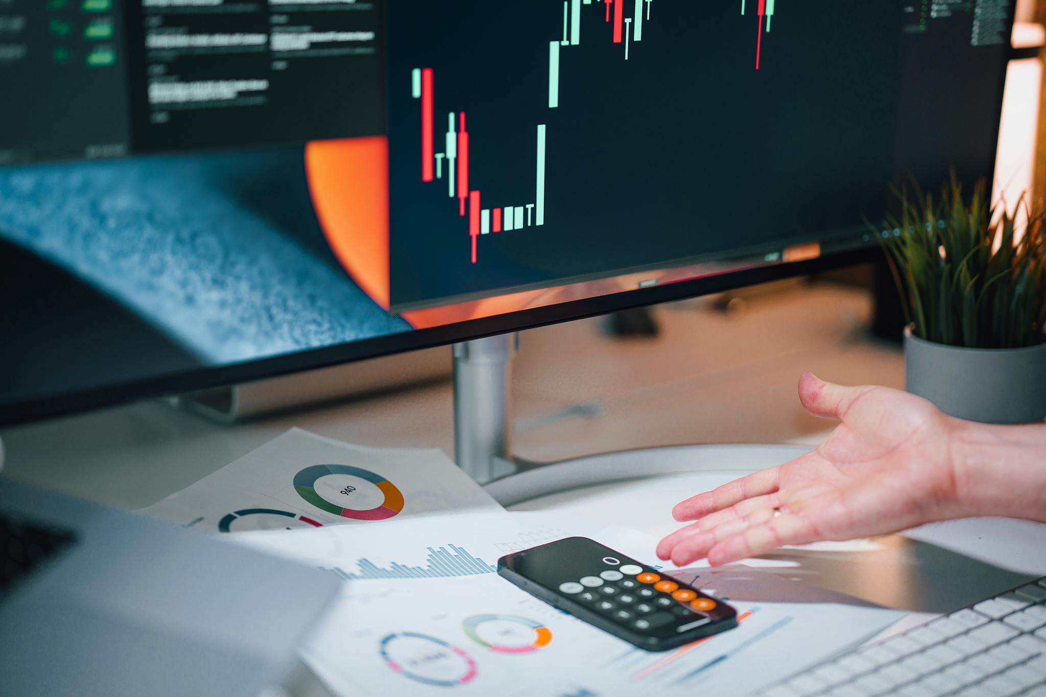 Businessman analyzing stock market data on computer monitor with documents and calculator.